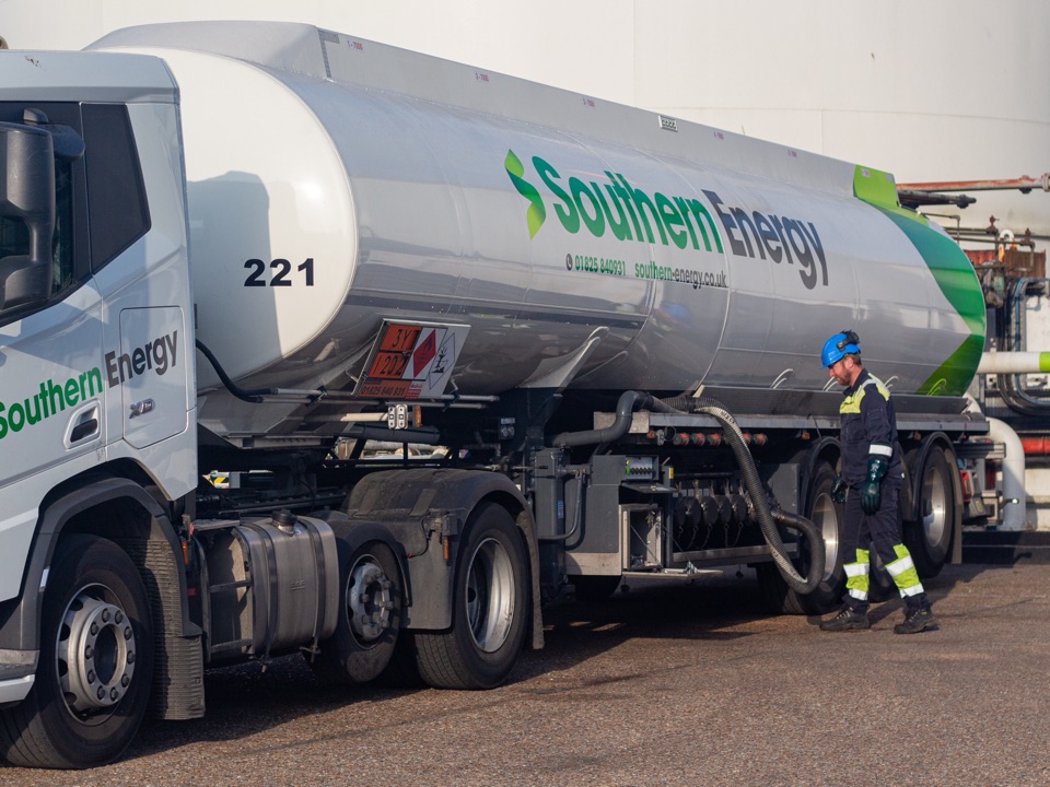 A Southern Energy articulated tanker at a fuel terminal, a worker in safety gear walking beside it